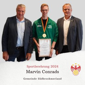 Drei Personen lächeln in die Kamera. Eine Person hält eine Urkunde und trägt eine Medaille um den Hals