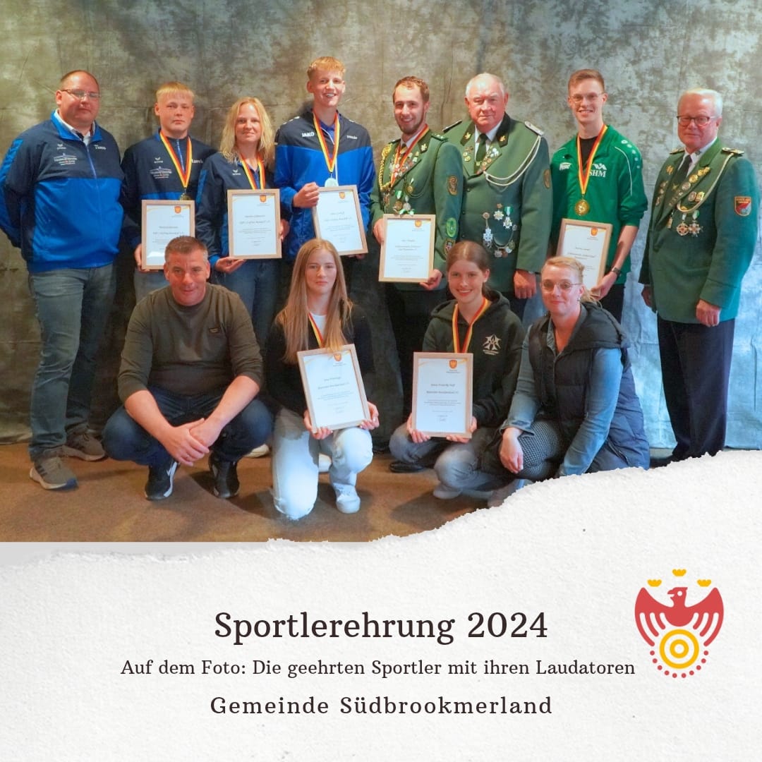 Mehrere Personen tragen jeweils eine Medaille um den Hals, eine Urkunde in den Händen und lächeln in die Kamera