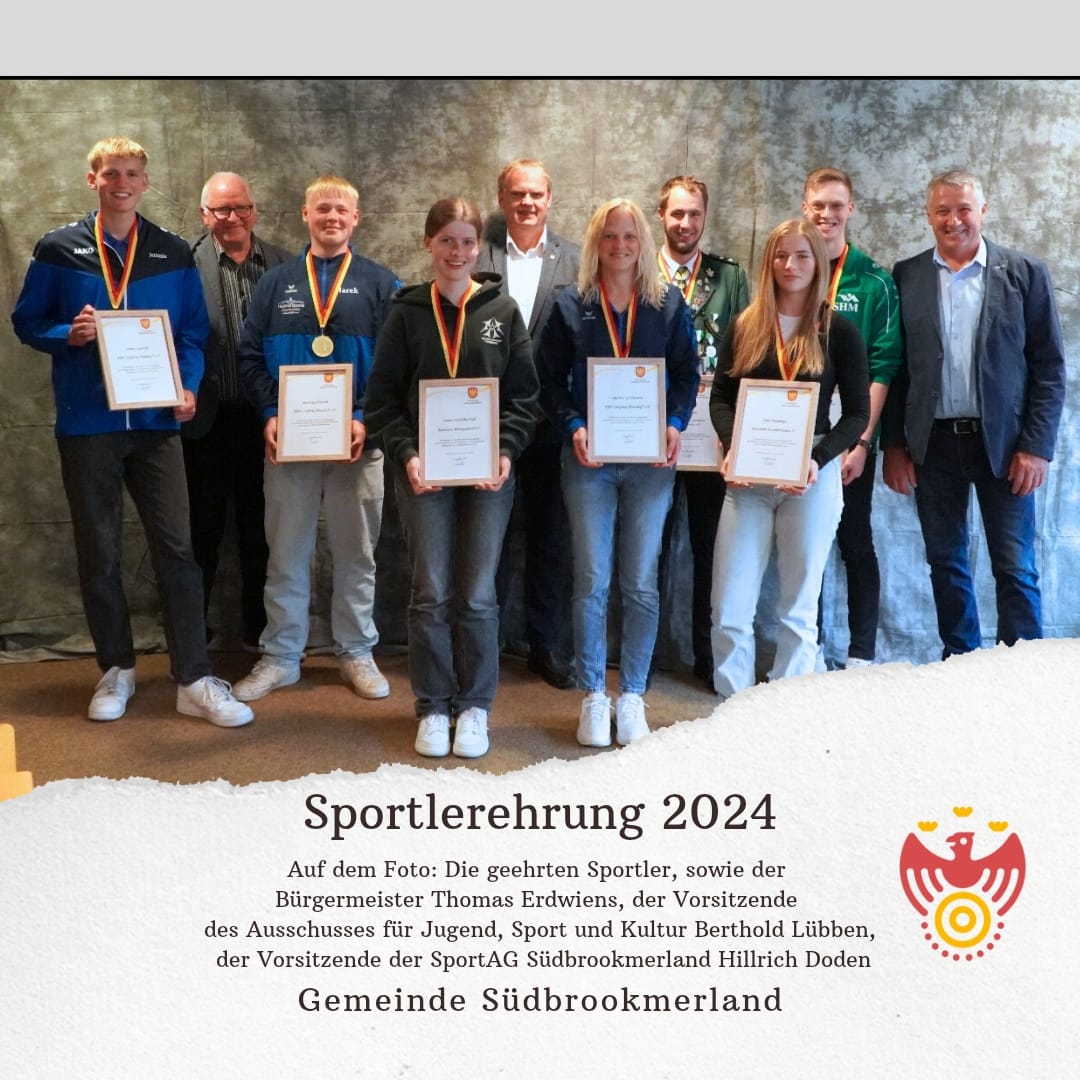 Mehrere Personen tragen jeweils eine Medaille um den Hals, eine Urkunde in den Händen und lächeln in die Kamera