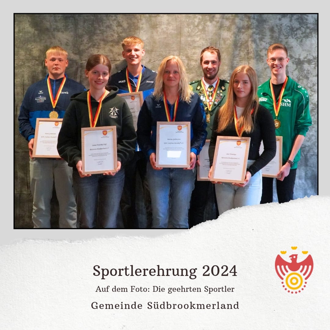 Mehrere Personen tragen jeweils eine Medaille um den Hals, eine Urkunde in den Händen und lächeln in die Kamera