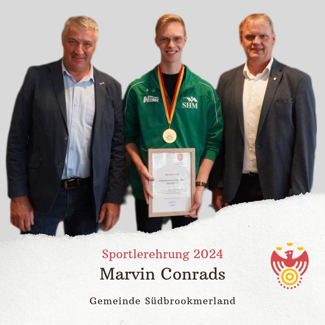 Drei Personen lächeln in die Kamera. Eine Person hält eine Urkunde und trägt eine Medaille um den Hals